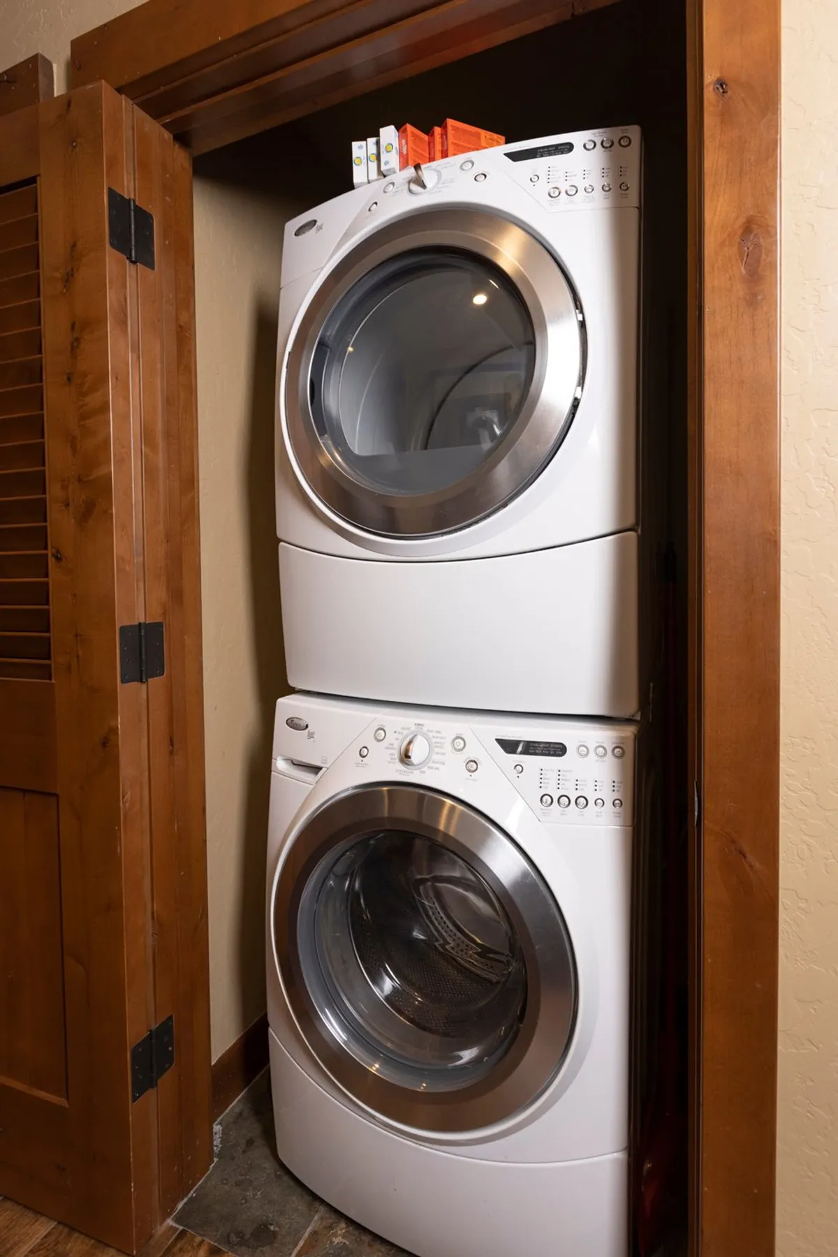 A practical laundry area featuring a stacked washer and dryer alongside shelves stocked with detergent. The space is organized for efficiency, making household chores straightforward and accessible.