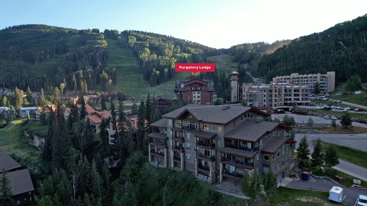 A panoramic exterior view showing Purgatory Lodge and nearby buildings nestled amongst scenic mountains at sunset. The tranquil landscape hints at other recreational possibilities and the natural beauty surrounding the village.