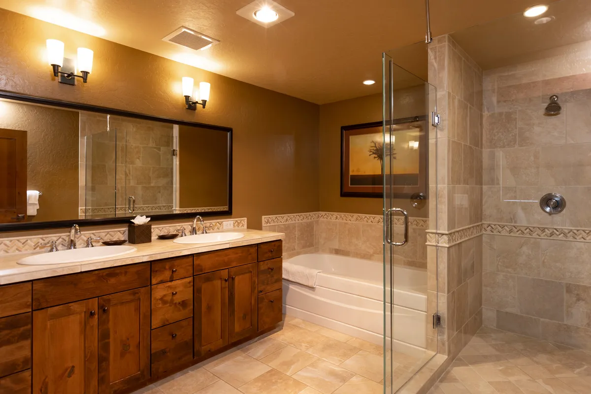 A serene bathroom with a double sink vanity, a glass shower enclosure, and decorative artwork. The space feels spa-like, offering both functionality and relaxation for morning routines or unwinding after outdoor adventures.